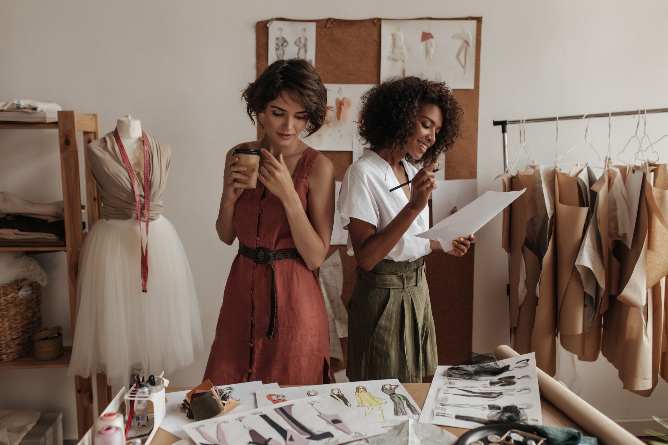Stylist reviewing sketches beside a rail of garments
